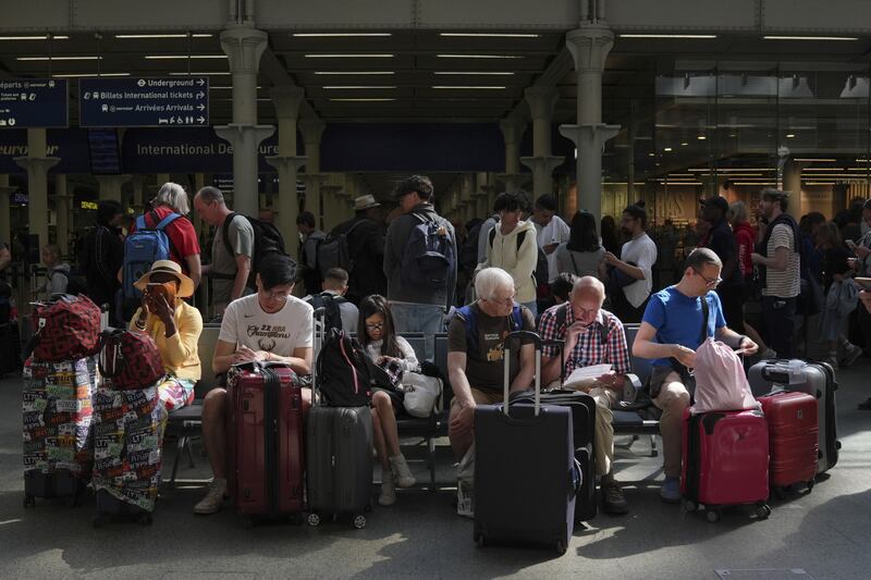 Families wait with luggage for the next departure