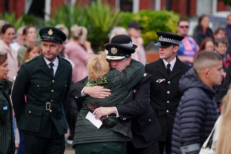 Two members of the emergency services embrace while waiting for the funeral of Southport stabbing victim Elsie Dot Stancombe