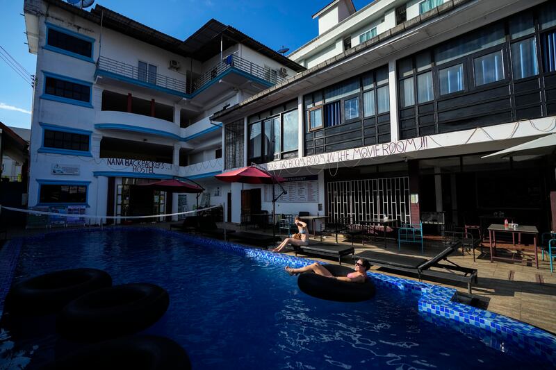 Foreign tourists relax at a swimming pool at Nana Backpack hostel in Vang Vieng, Laos (Anupam Nath/AP)