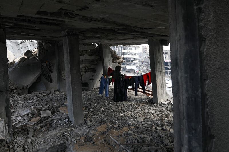 A Palestinian woman hangs the laundry inside her home, which was destroyed in the Israeli bombardment of the Gaza Strip (Jehad Alshrafi/AP)