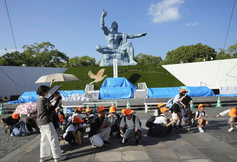 Visitors to Nagasaki’s Peace Park crouch down after an earthquake alert was issued (Kyodo News/AP)