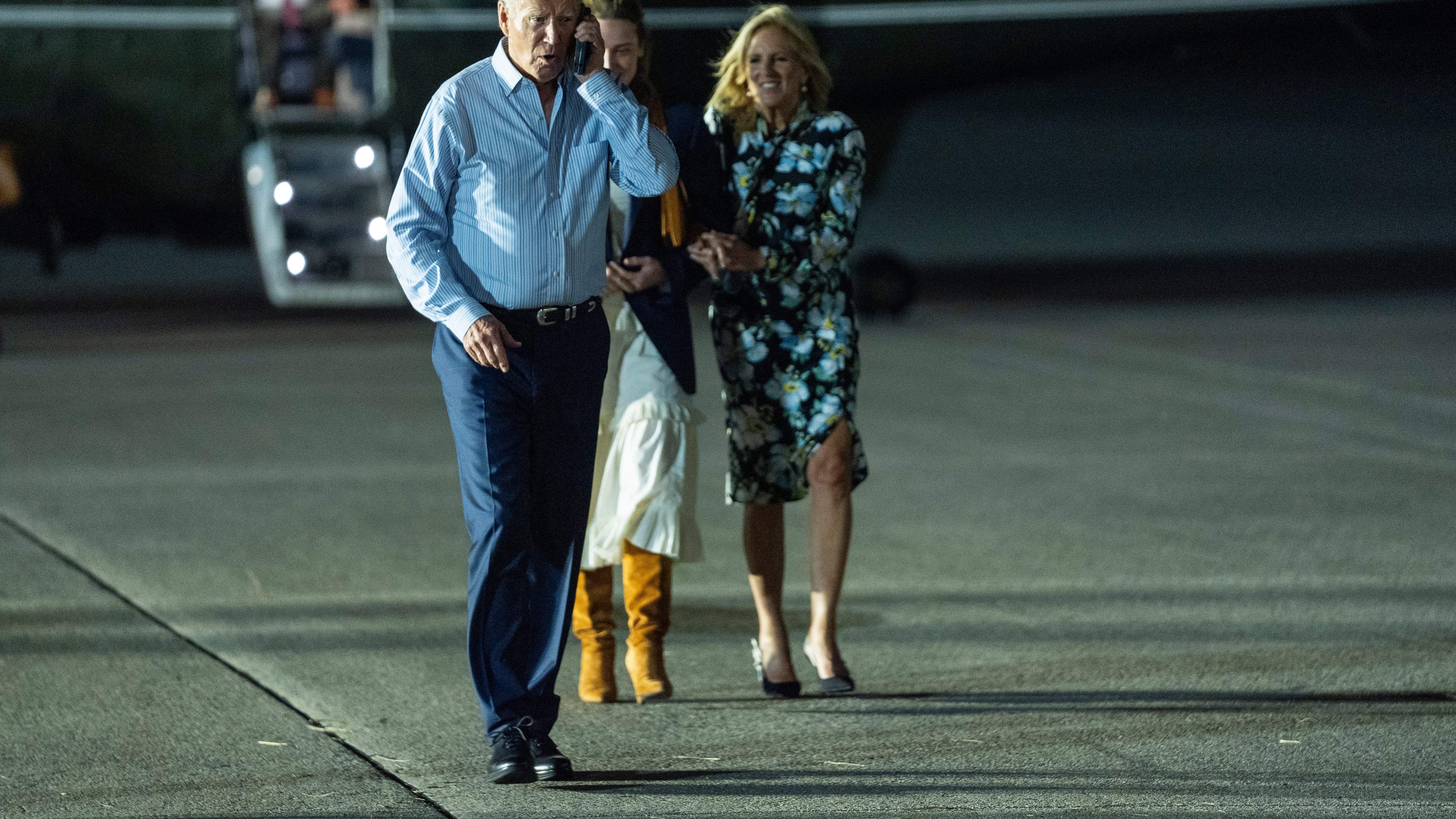 President Joe Biden, left, talks on the phone as he walks to board Air Force One (Evan Vucci/AP)
