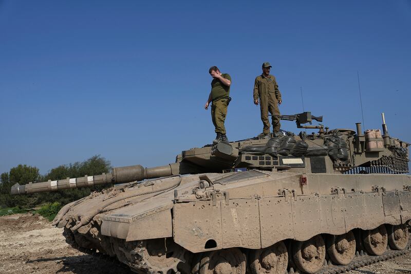 Israeli soldiers stand on their tank near the Israel-Gaza border (Tsafrir Abayov/AP)