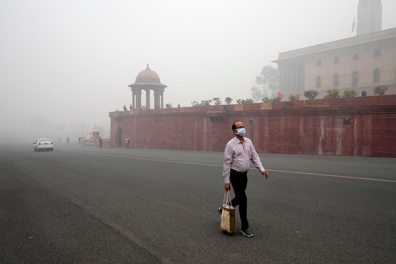 An office goer walks wearing a face mask amid a thick layer of smog in New Delhi (Manish Swarup/AP)