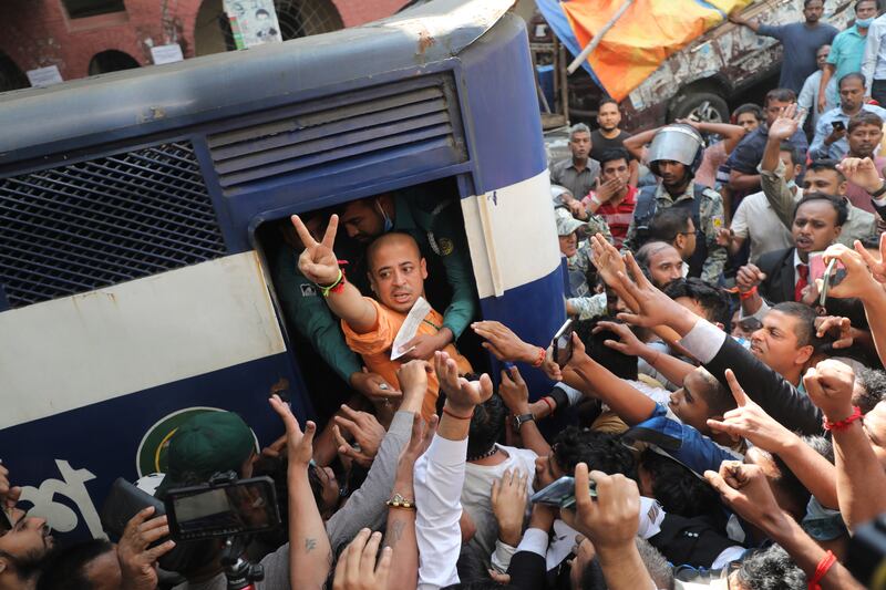 Bangladeshi Hindu leader Krishna Das Prabhu makes a victory sign as he is taken in a police van after a court in Chattogram ordered him to be detained pending further proceedings (AP)