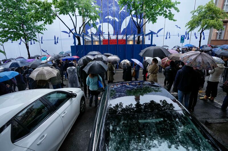 People gather in front of the school during a memorial ceremony (Darko Vojinovic/AP)