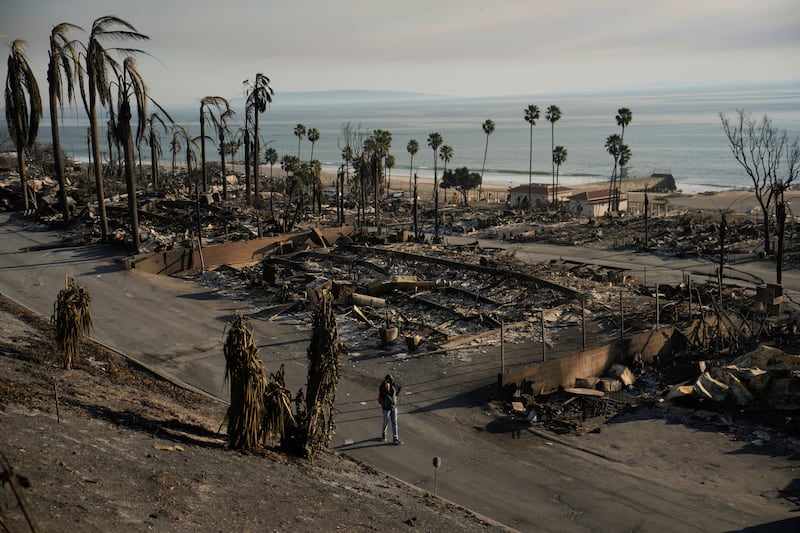 A person walks past damage from the Palisades Fire on Friday (John Locher/AP)