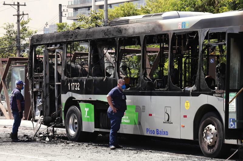 Police inspect a bus that caught fire after a small aircraft crashed on an avenue in Sao Paulo (Ettore Chiereguini/AP)