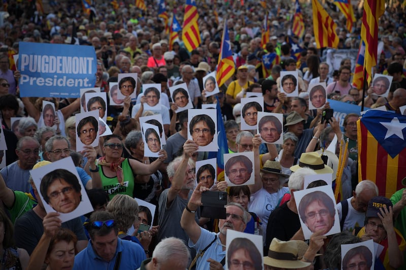 Supporters of Catalan independence leader Carles Puigdemont hold his portrait as they wait for his arrival near the Catalan parliament in Barcelona (Emilio Morenatti/AP)