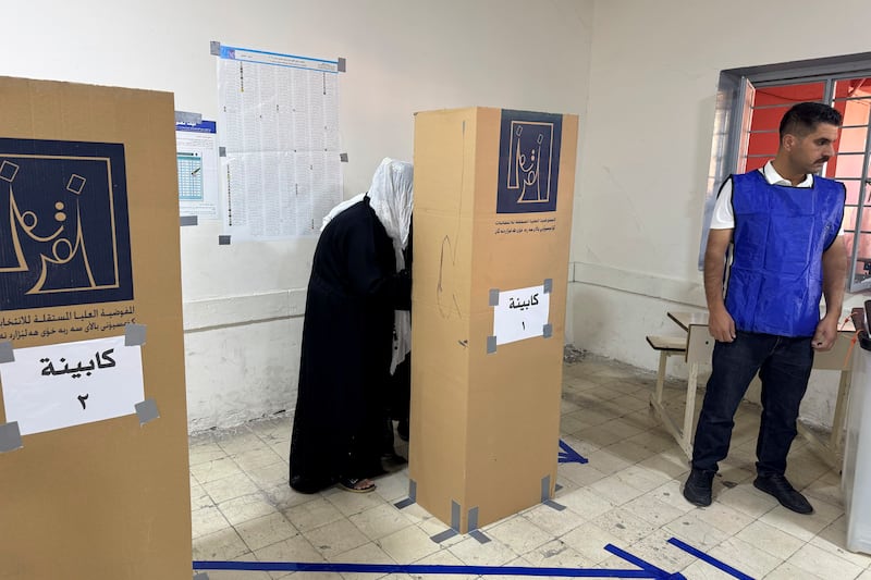 A woman enters a voting booth in Irbil (Salar Salim/AP)