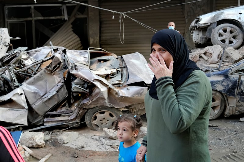 A woman passes in front of destroyed cars at the site of Thursday’s Israeli airstrike in Beirut (AP Photo/Hussein Malla)