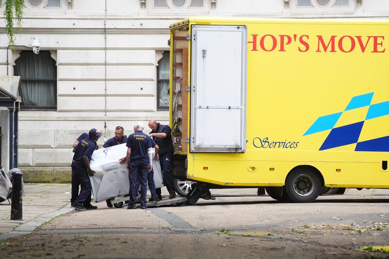 Removal men load an upright piano into the van at the back of Downing Street