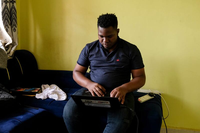 Ugandan human rights activist Kennedy Pius reads a letter from USAid on his laptop at home in Kampala, Uganda (Hajarah Nalwadda/AP)