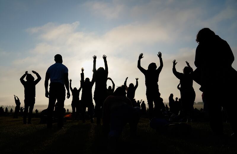 People practice yoga as the sun rises during the Summer Solstice at Stonehenge in Wiltshire. (Andrew Matthews/PA Wire)