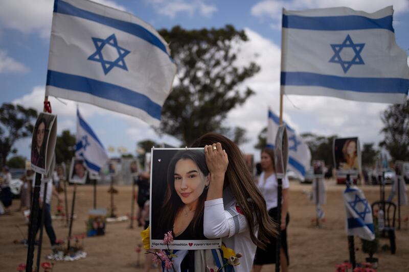 A woman touches a picture of a relative as she attends Israel’s annual Memorial Day (Leo Correa/AP)
