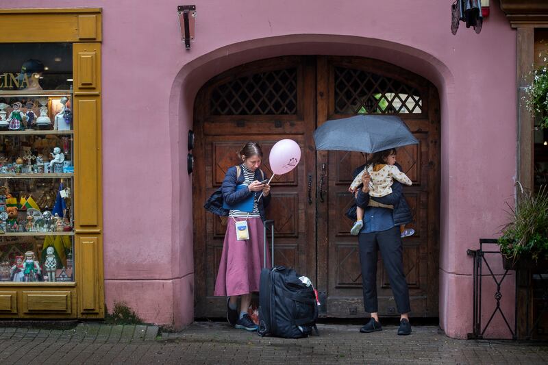 People shelter from the rain in Vilnius, Lithuania (Mindaugas Kulbis/AP)