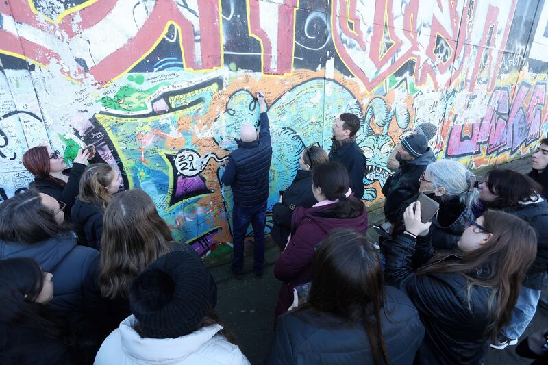 Tourists sign the Peace Wall at Cupar Way in west Belfast. Picture by Mal McCann