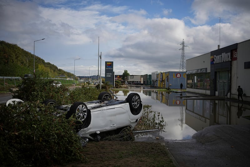 An overturned car in the car park of a shopping centre in Givors, central France, after torrential rains and flooding submerged roads and railways (Laurent Cirpiani/AP)