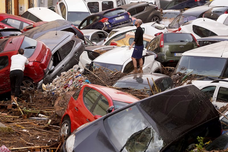 Residents look at cars piled up after being swept away by floods in Valencia (Alberto Saiz/AP)