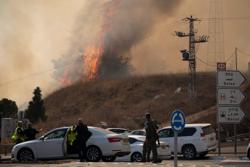 Members of the Israeli forces watch a fire after a rocket, fired from Lebanon, hit an area near the town of Rosh Pinna in northern Israel (Leo Correa/AP)