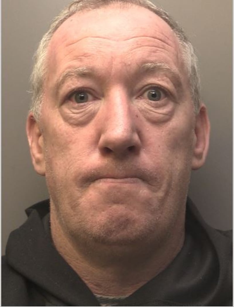 Police mugshot of a man in a black shirt