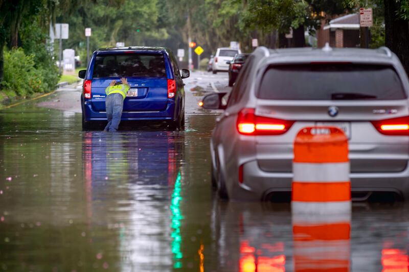 The driver of a stranded vehicle pushes his van out of a flooded street after heavy rain from Tropical Storm Debby in Savannah, Georgia