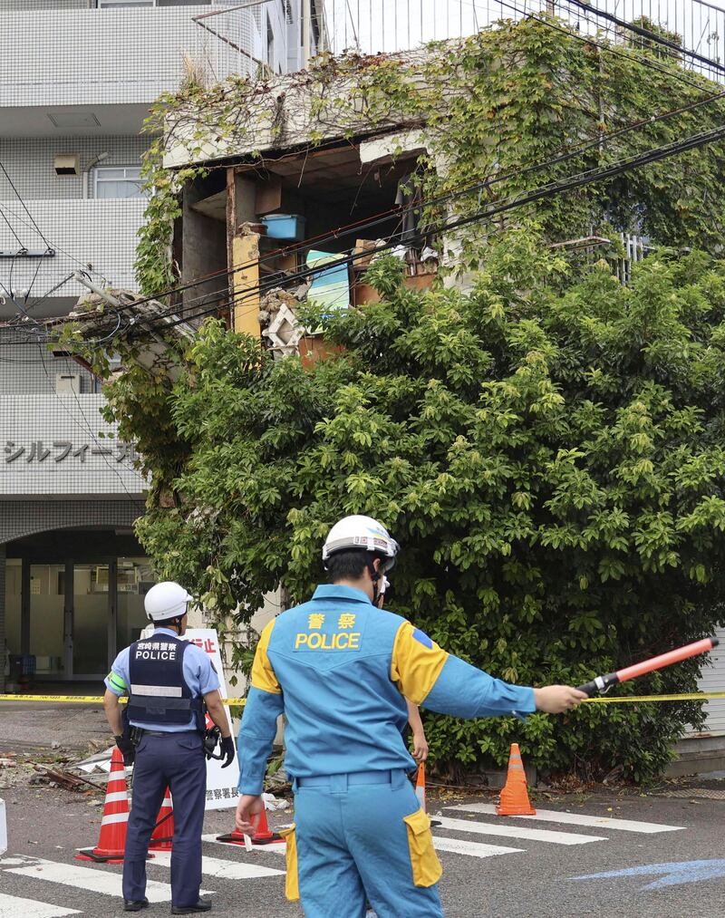 Police stand outside a damaged building in Miyazaki, western Japan, following the earthquake (Kyodo News/AP)