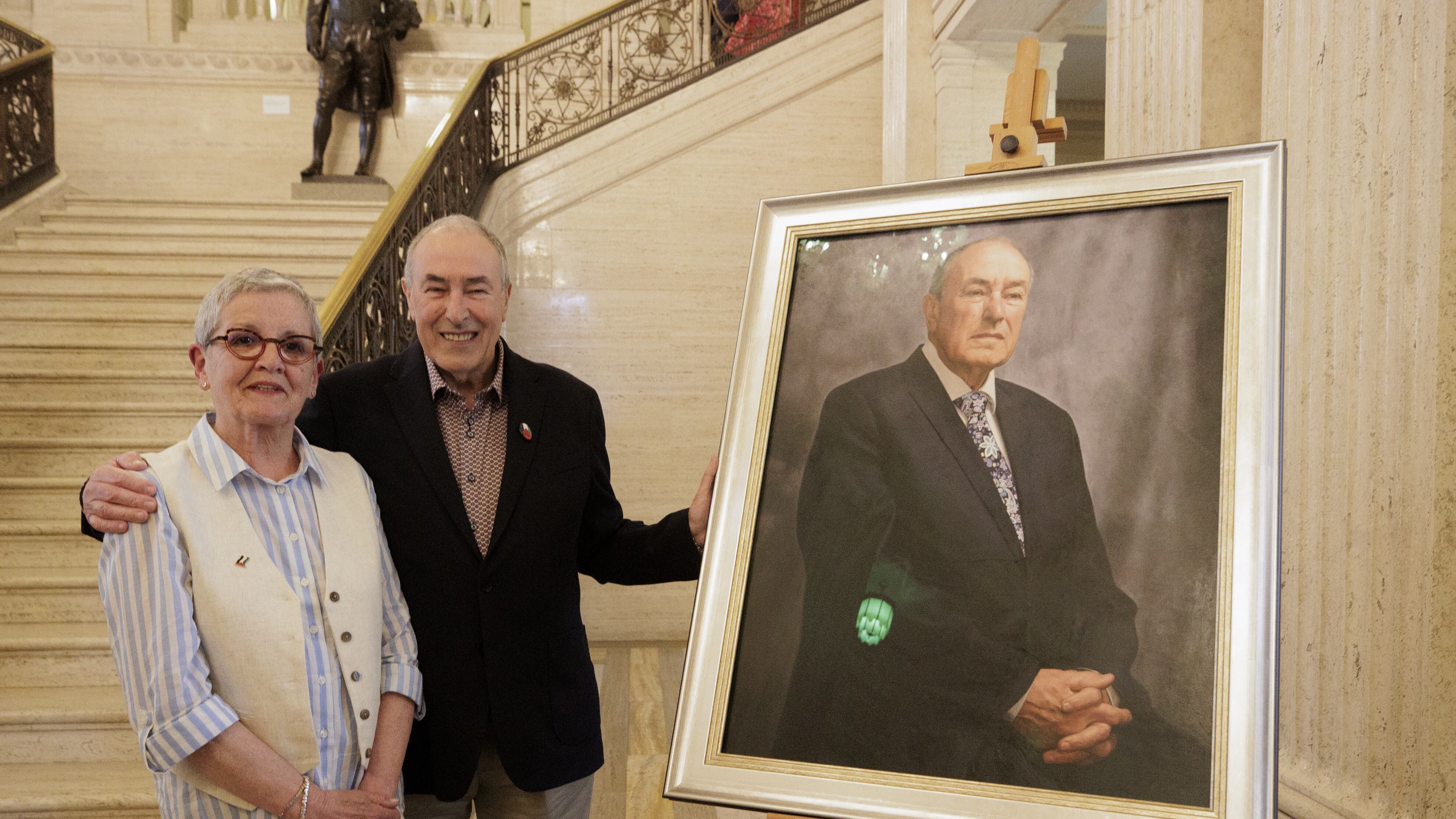 Former Stormont Assembly speaker Mitchel McLaughlin and his wife Marylou stand beside a portrait of himself, painted by Catherine Creaney, as it is unveiled in the Great Hall at Parliament Buildings
