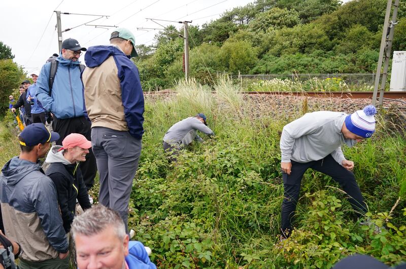 Spectators search for Rory McIlroy’s ball after he drove out of bounds on the 11th