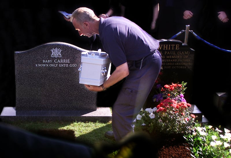 A grave digger lays to rest the remains of baby Carrie  at Knockbreda cemetery in 2002