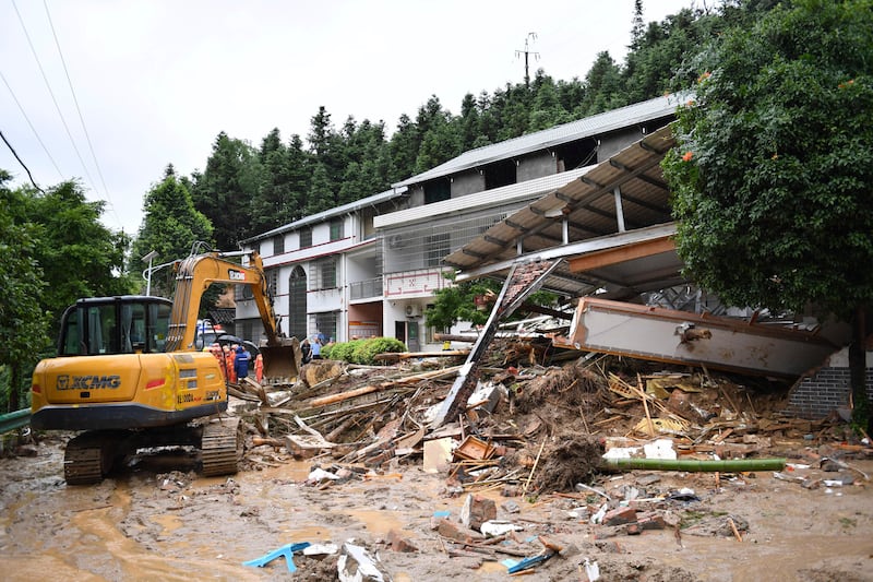 An excavator works near a collapsed building in the aftermath of the landslide in Yuelin village in central China’s Hunan Province (Chen Zhenhai/Xinhua News Agency/AP)