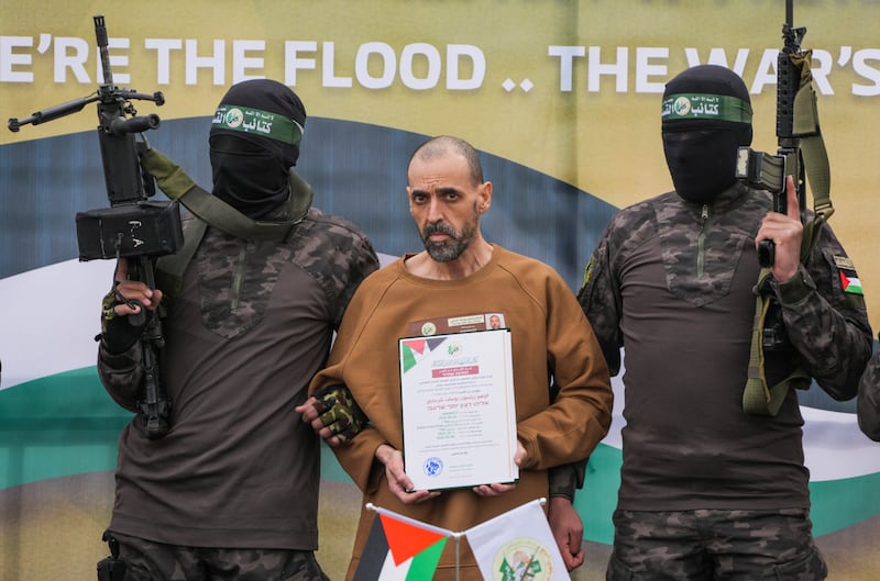 Israeli captive Eli Sharabi, who has been held hostage by Hamas in Gaza since October 7, 2023, stands on a stage with Hamas fighters (Abdel Kareem Hana/AP)