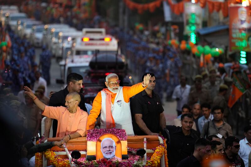 Indian Prime Minister Narendra Modi and Yogi Adityanath, chief minister of Uttar Pradesh, greet supporters during a roadshow in Varanasi (Rajesh Kumar/AP)