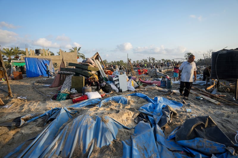 Palestinians look at the destruction after an Israeli air strike on a crowded tent camp in Muwasi (Abdel Kareem Hana/AP)