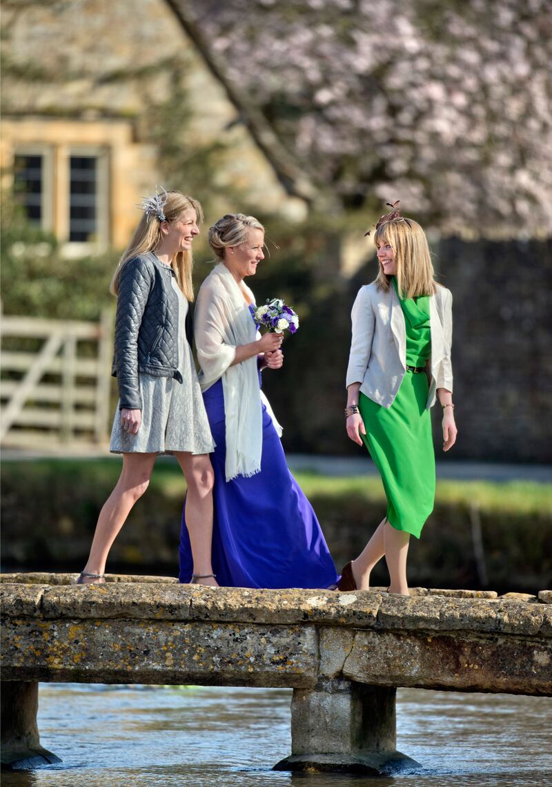 E3NCYE Wedding guests cross a stone bridge in the village of Lower Slaughter, Gloucestershire UK