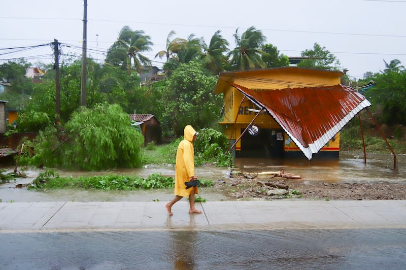 A person walks in the rain after the passing of Hurricane John in Marquelia, Mexico (Luis Alberto Cruz/AP)