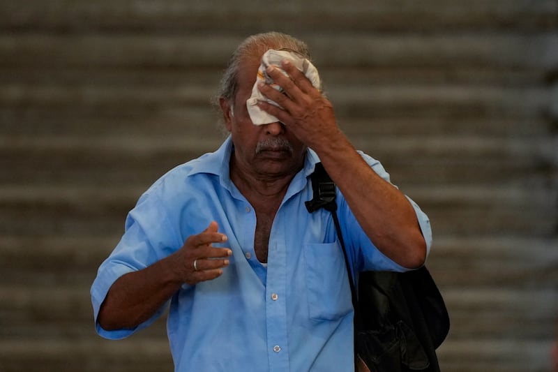 A passenger wipes sweat from his forehead as he waits for a train in Colombo during the national rail strike (Eranga Jayawardena/AP)