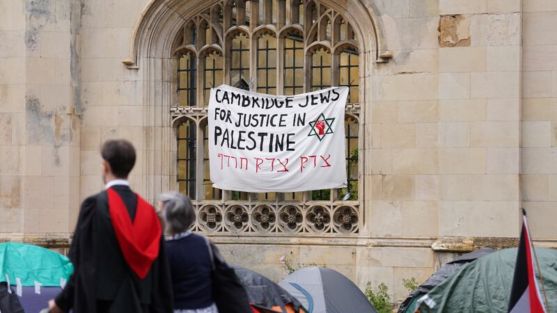 Graduating students pass an encampment protest over the Gaza conflict on the grounds of Cambridge University