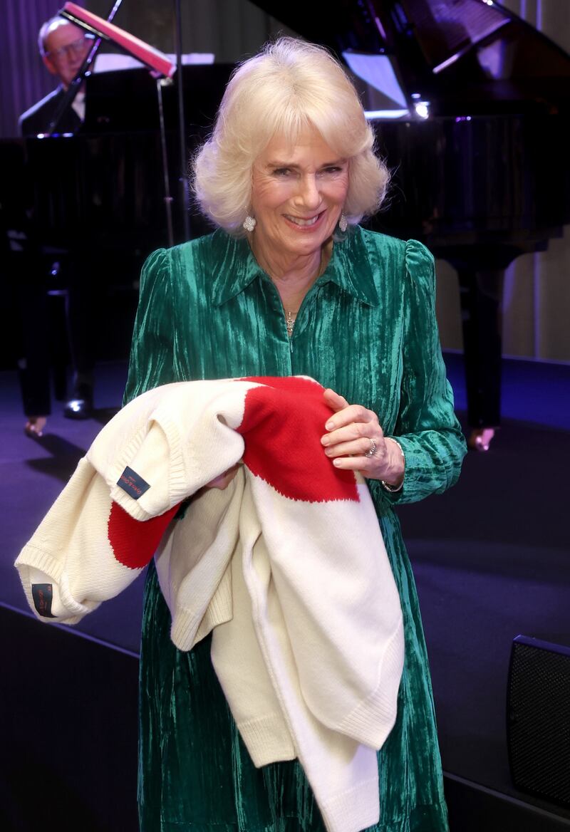 Queen Camilla smiles as she holds gifts of Valentine’s Day jumpers