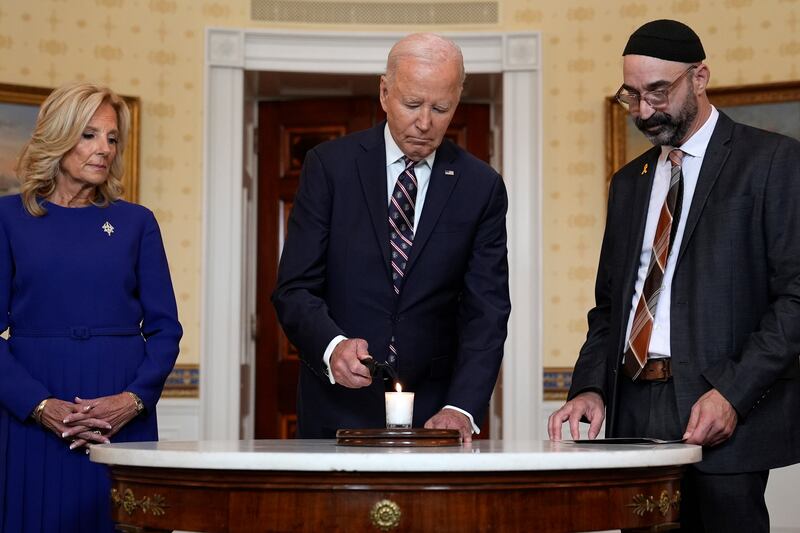 US President Joe Biden, with first lady Jill Biden and Rabbi Aaron Alexander, lights a memorial candle in the Blue Room of the White House (Susan Walsh/AP)