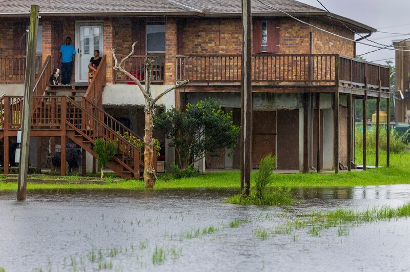 Residents sit on their front porch as they watch water rise as the effects of Hurricane Francine are felt along the Louisiana coast (Chris Granger/The Times-Picayune/The New Orleans Advocate via AP)