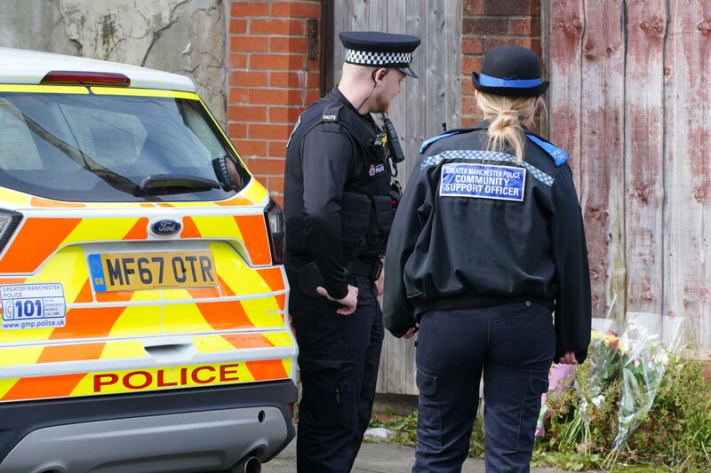Police officers looking at flowers left outside Mr Patience’s property in Radcliffe, Greater Manchester