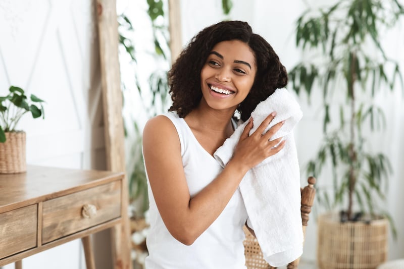 Young woman smiling and drying her wet hair with a towel