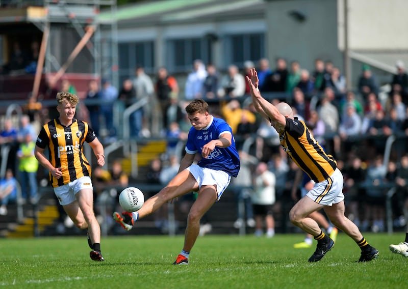 A Clan na Gael playing kicking a gaelic football with a Crossmaglen player attempting to block