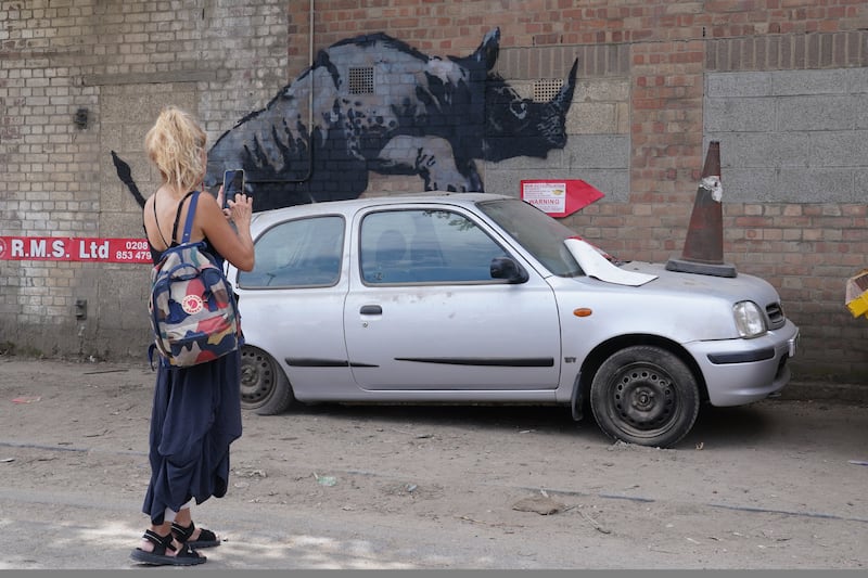 A woman takes a photograph of the Banksy rhino