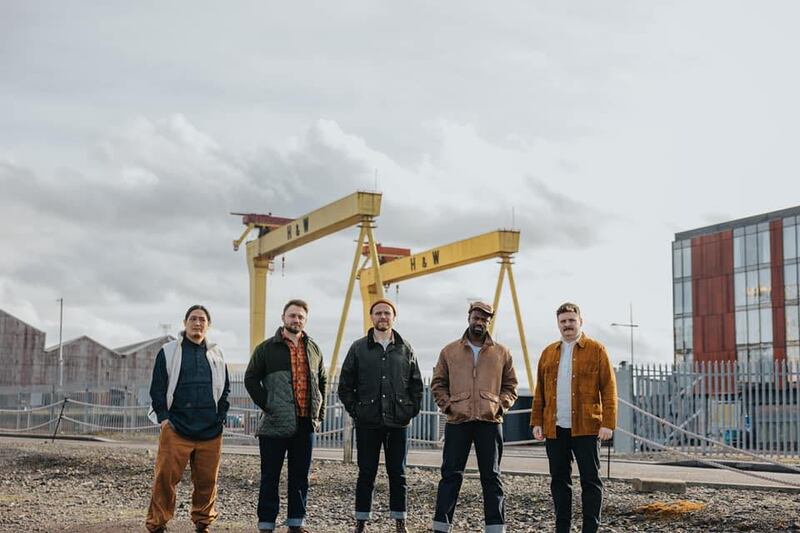 The members of Rend Collective standing beside the famous Samson and Goliath cranes in Belfast