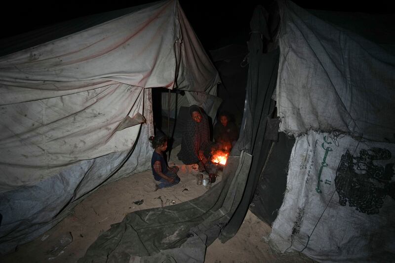 A displaced family sit round the fire in their tent at a camp in Deir al-Balah, Gaza Strip (Abdel Kareem Hana/AP)