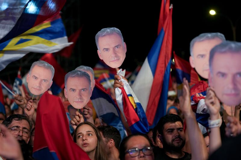 Supporters hold face cut-outs of Yamandu Orsi, candidate for the Broad Front after polls closed in the presidential run-off election in Montevideo, Uruguay (AP/Natacha Pisarenko)