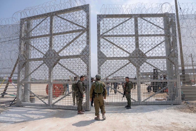 Israeli soldiers gather near a gate to walk through an inspection area for trucks carrying humanitarian aid supplies bound for the Gaza Strip (AP)