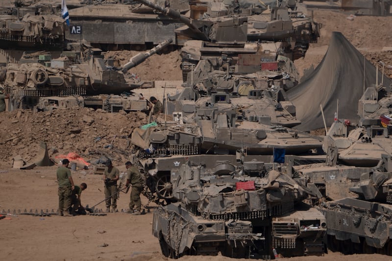 Israeli soldiers work on a tank in a staging area near the Israeli-Gaza border in southern Israel (AP)